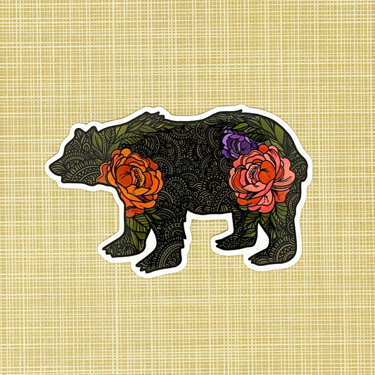 A bear illustration made into a vinyl sticker laying on a patterned background.