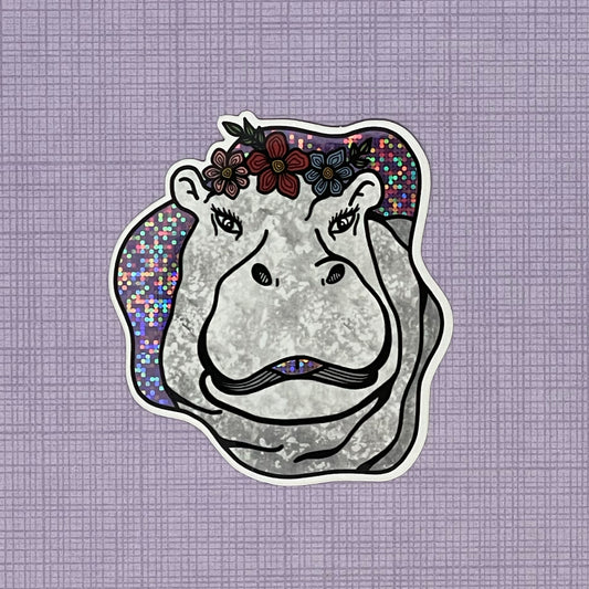 A fun and sassy hippo illustration made into a glittery sticker. Laying on top of a purple pattern background.