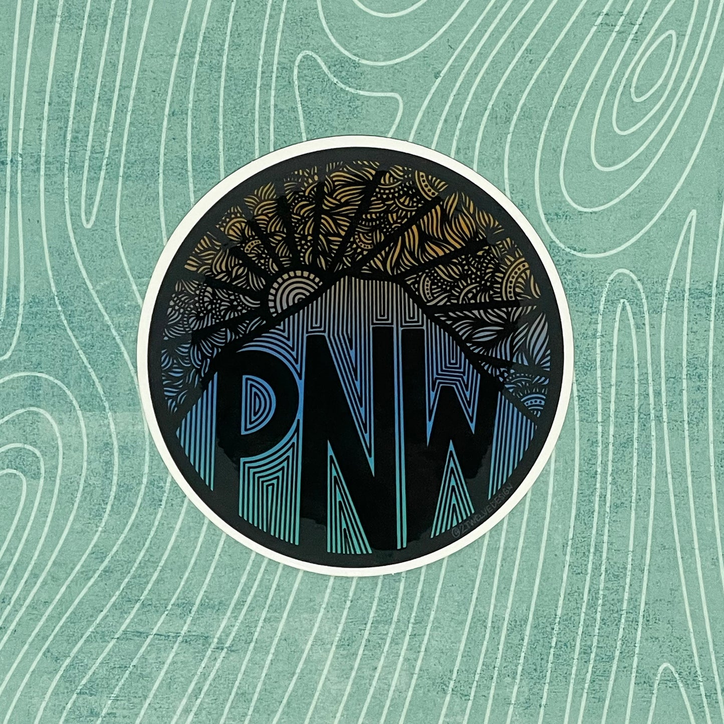 A PNW sticker with intricate designs, mountain and sun.
