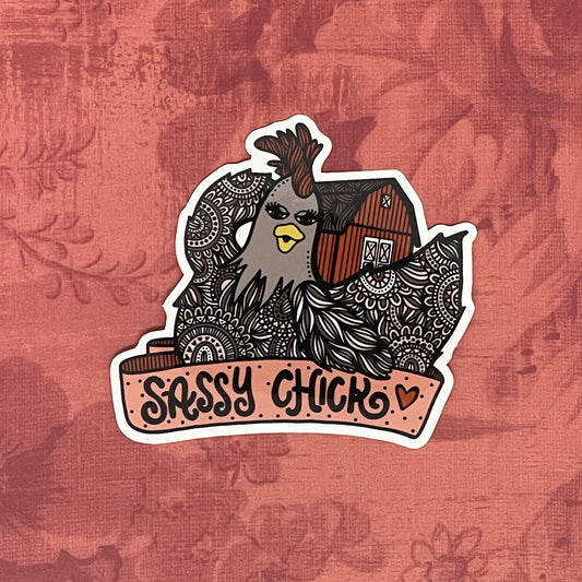 A cute chicken and barn illustration with a banner that reads "Sassy Chick", made into a vinyl sticker. Laying on a red texture background.