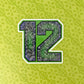A stylized number 12 with a green, blue and black ornamental patterned fill, outlined in white, centered on a light green patterned background.