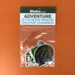 Packaged Adventure sticker set with label on a textured brown background.