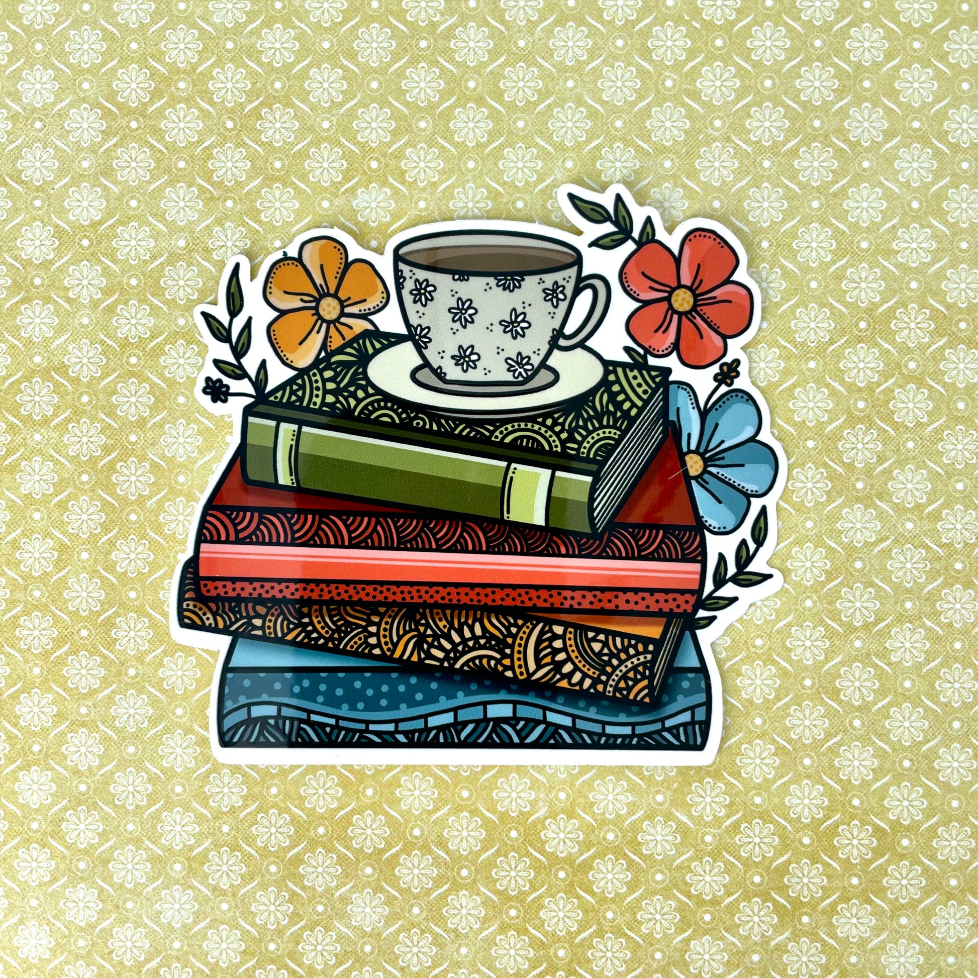 Illustrated sticker of a stack of books with a coffee cup and florals. Laying on top of a yellow background.