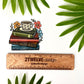 Decorative sticker of books and a coffee cup with flowers, surrounded by leaves and accompanied by a wooden ruler to show actual size.