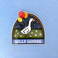Sticker with a goose holding balloons and 'Silly Goose' text laying on a blue background