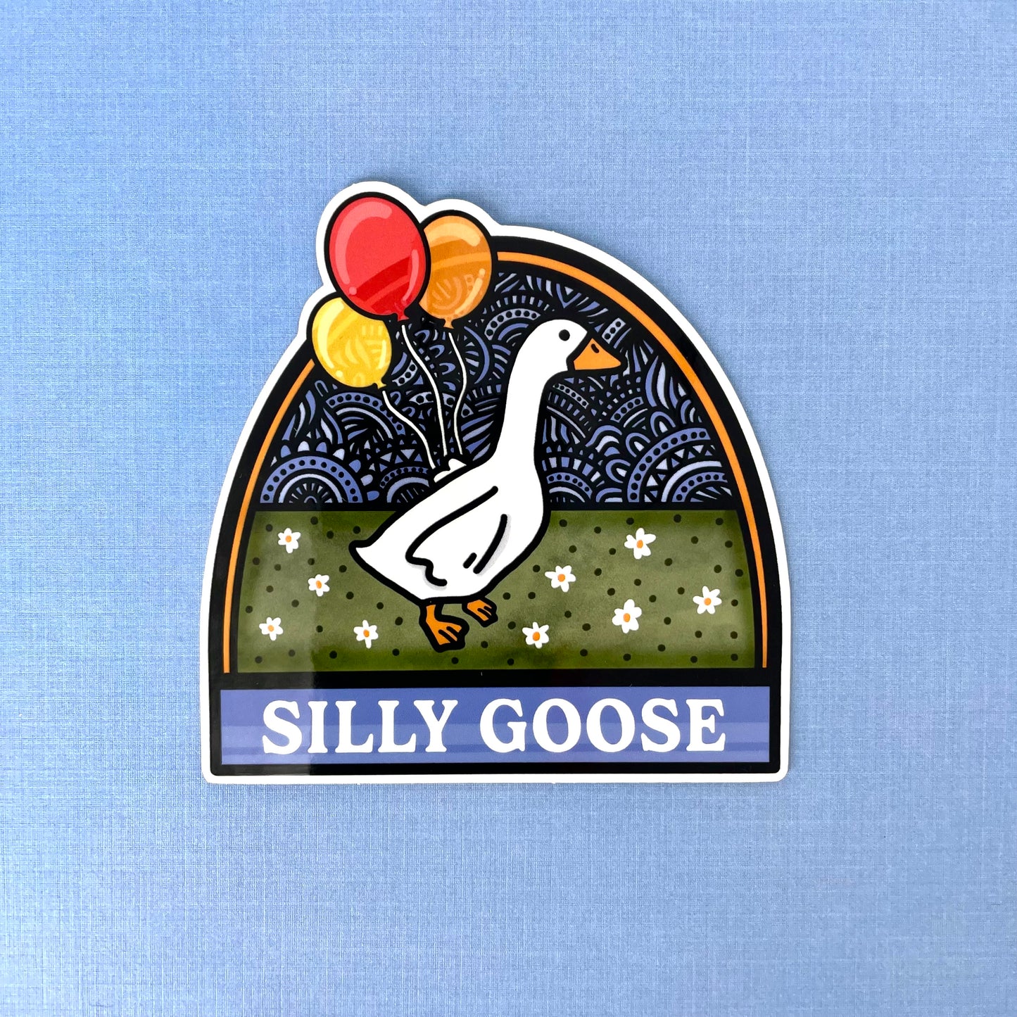 Sticker with a goose holding balloons and 'Silly Goose' text laying on a blue background