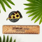 A hand illustrated pizza drawing made into a vinyl sticker. Laying on a white background surrounded by green palm leaves.