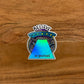An illustration of a spaceship with "Believe In Yourself" made into a holographic sticker. Laying flat on a wooden surface.