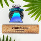 A holographic sticker of a spaceship with the quote "Believe In Yourself" laying on a white background surrounded by leaves with a ruler to show actual size.