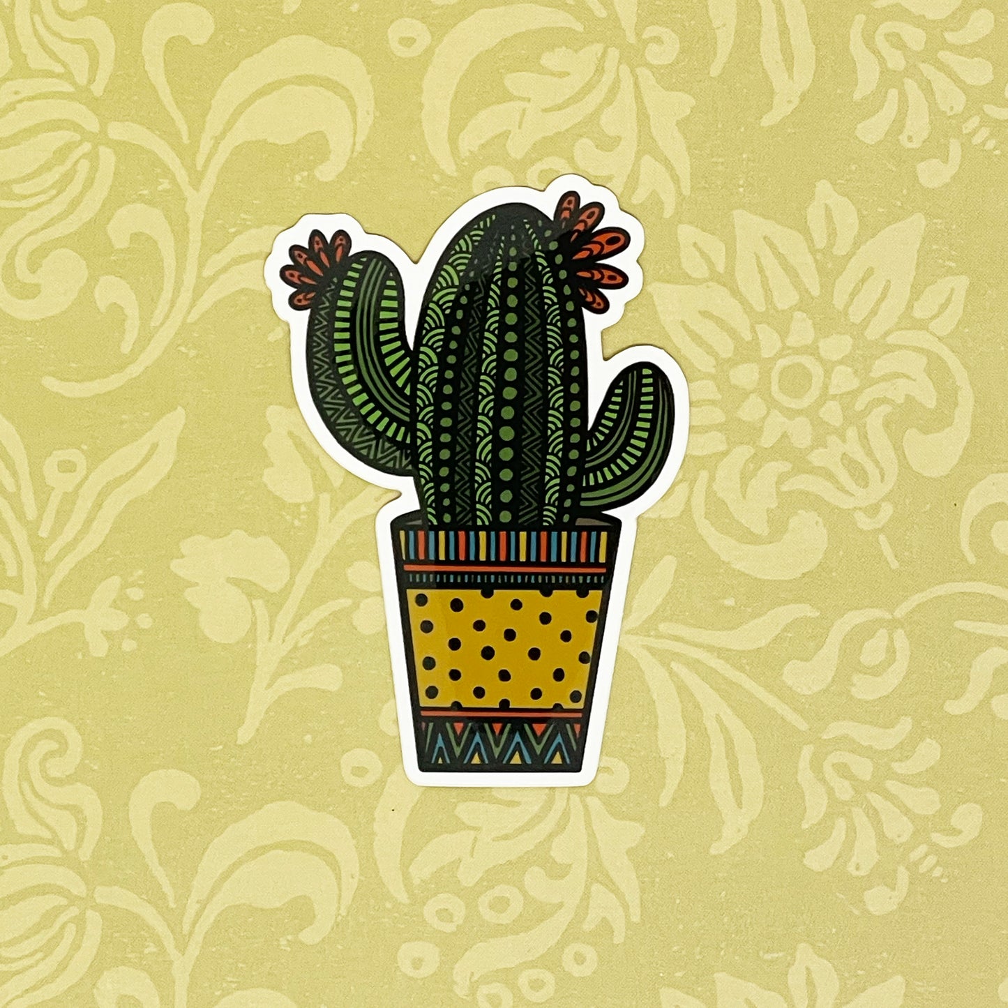 Potted cactus illustration made into a durable sticker. Laying on a light yellow background. 