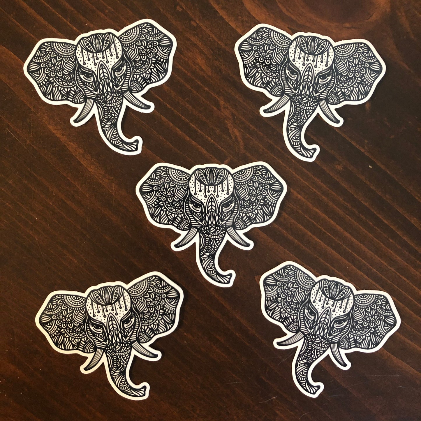 A group of five elephant stickers laying on a wooden surface.