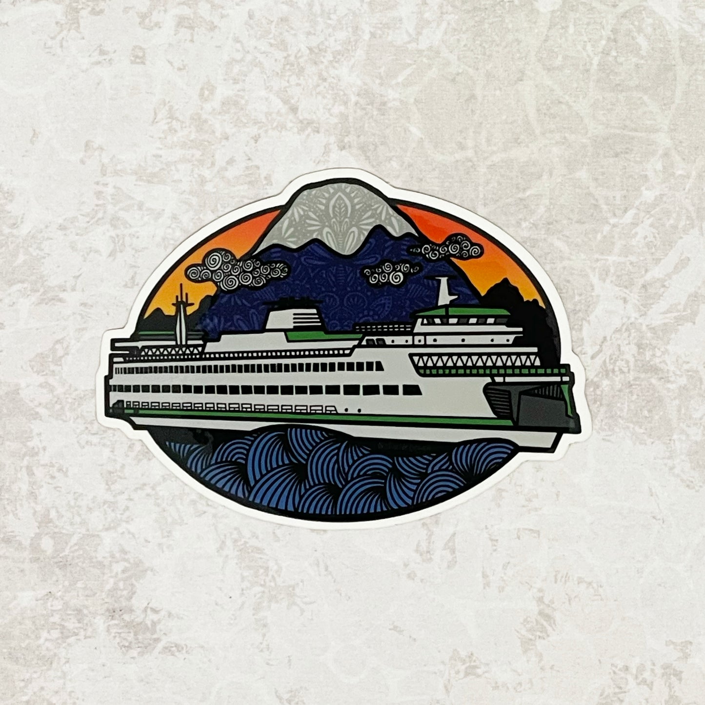 An illustration of a Washington State Ferry in the water with a mountain in the background - made into a vinyl sticker. Laying on a patterned gray surface.