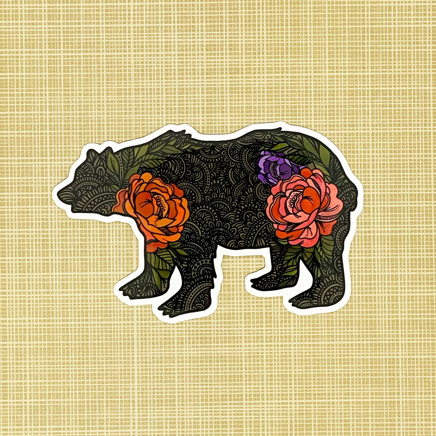 A bear illustration made into a vinyl sticker laying on a patterned background.