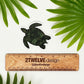 A green turtle sticker laying on a white surface above a ruler that says "2Twelve Design" surrounded by palm leaves