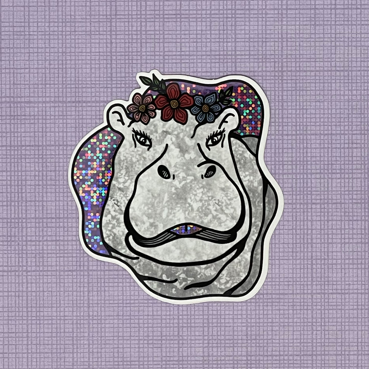 A fun and sassy hippo illustration made into a glittery sticker. Laying on top of a purple pattern background. 