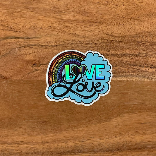 A die-cut holographic sticker with a hand-drawn love is love illustration, featuring a rainbow and the phrase 'love is love' in a circular blue font.