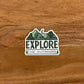 Mountain and moon illustration with "Explore The Outdoors" made into a vinyl sticker. Laying on a wooden surface.