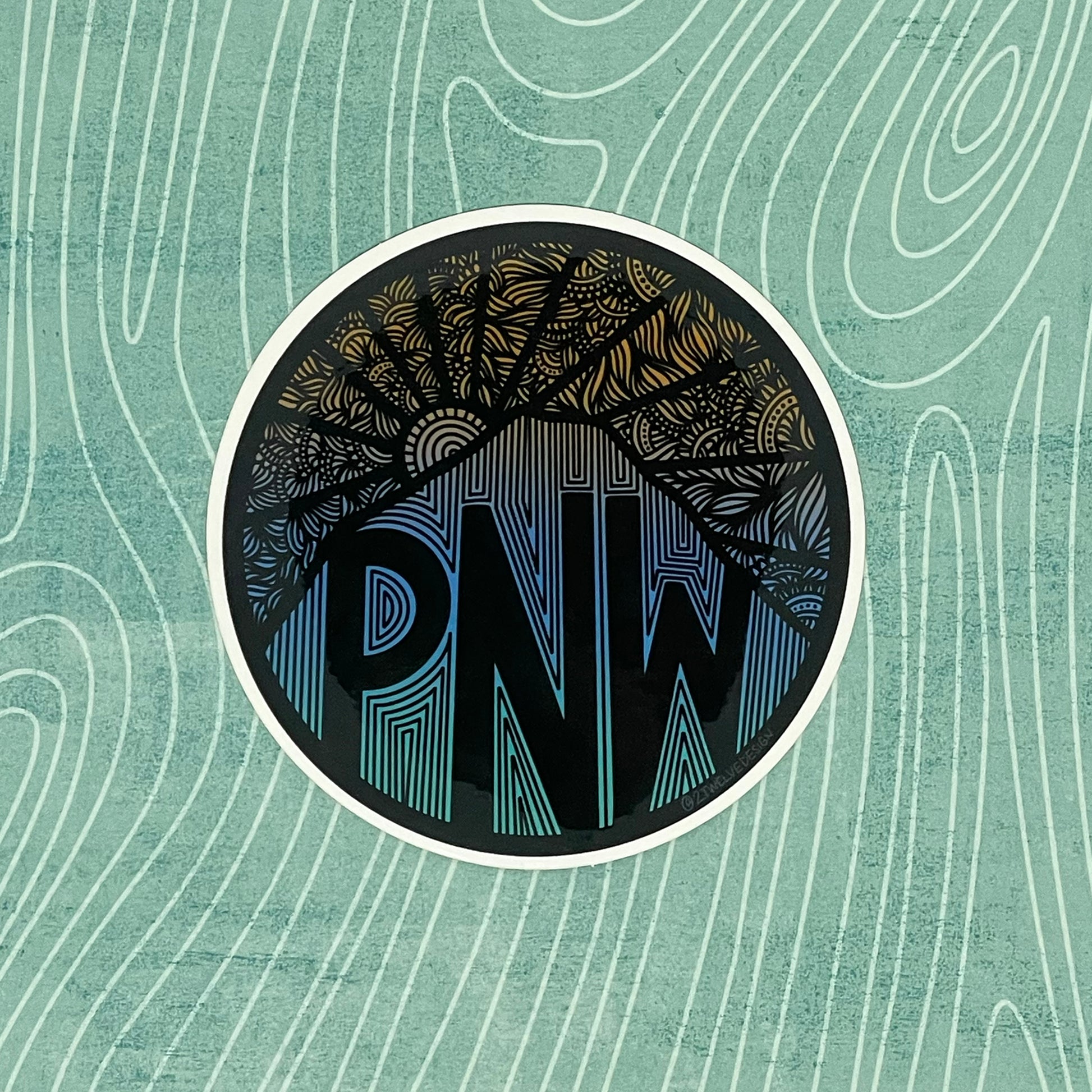 A PNW sticker with intricate designs, mountain and sun.