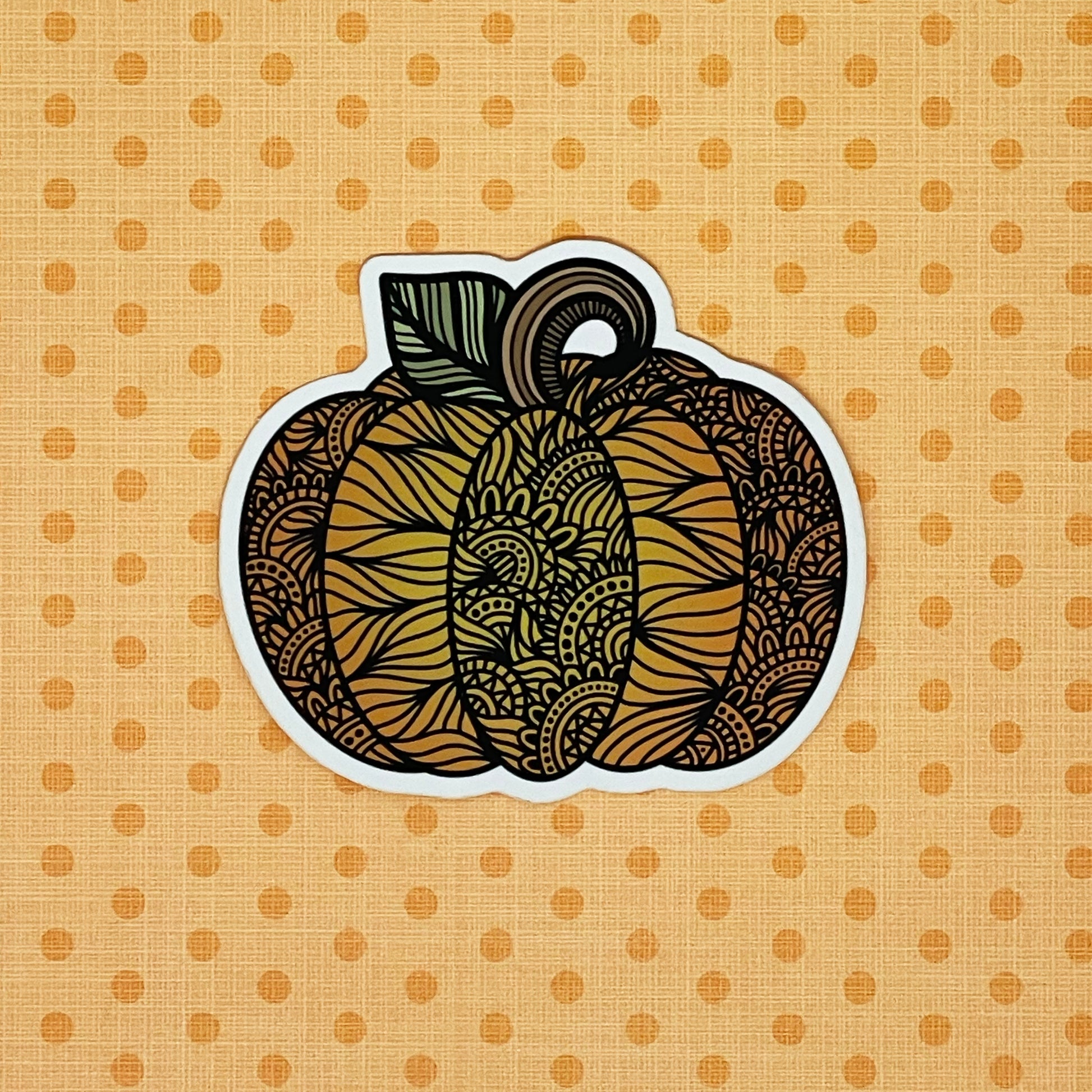 Zentangle inspired pumpkin illustration made into a diecut sticker. Laying on an orange pattern background.