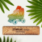 A rainbow color illustration of a roller skate turned into a die-cut sticker. Laying on a white surface surrounded by green palm leaves.