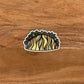 A fun, detailed illustrated taco sticker laying on a wood surface.
