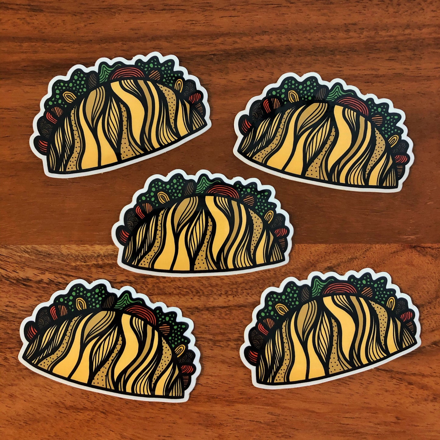 A group of five taco stickers laying on a wood surface