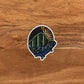 A detailed trout and mountain illustration made into a die-cut sticker. Laying on a wooden background.