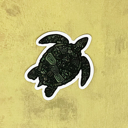 Detailed turtle illustration made into a sticker laying on a yellow textured surface.